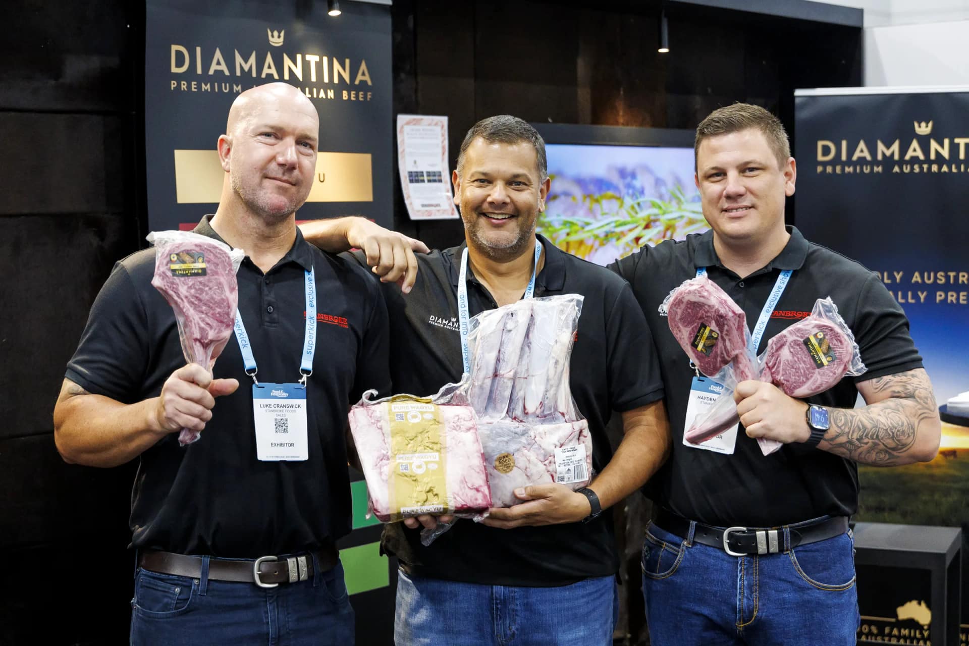 Three exhibitors holding packed beef cuts at the Diamantina Premium Australian Beef stand