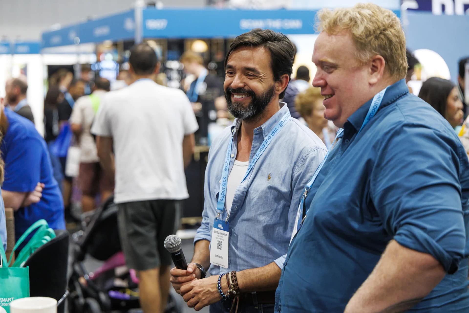 A speaker holding a microphone on the busy show floor