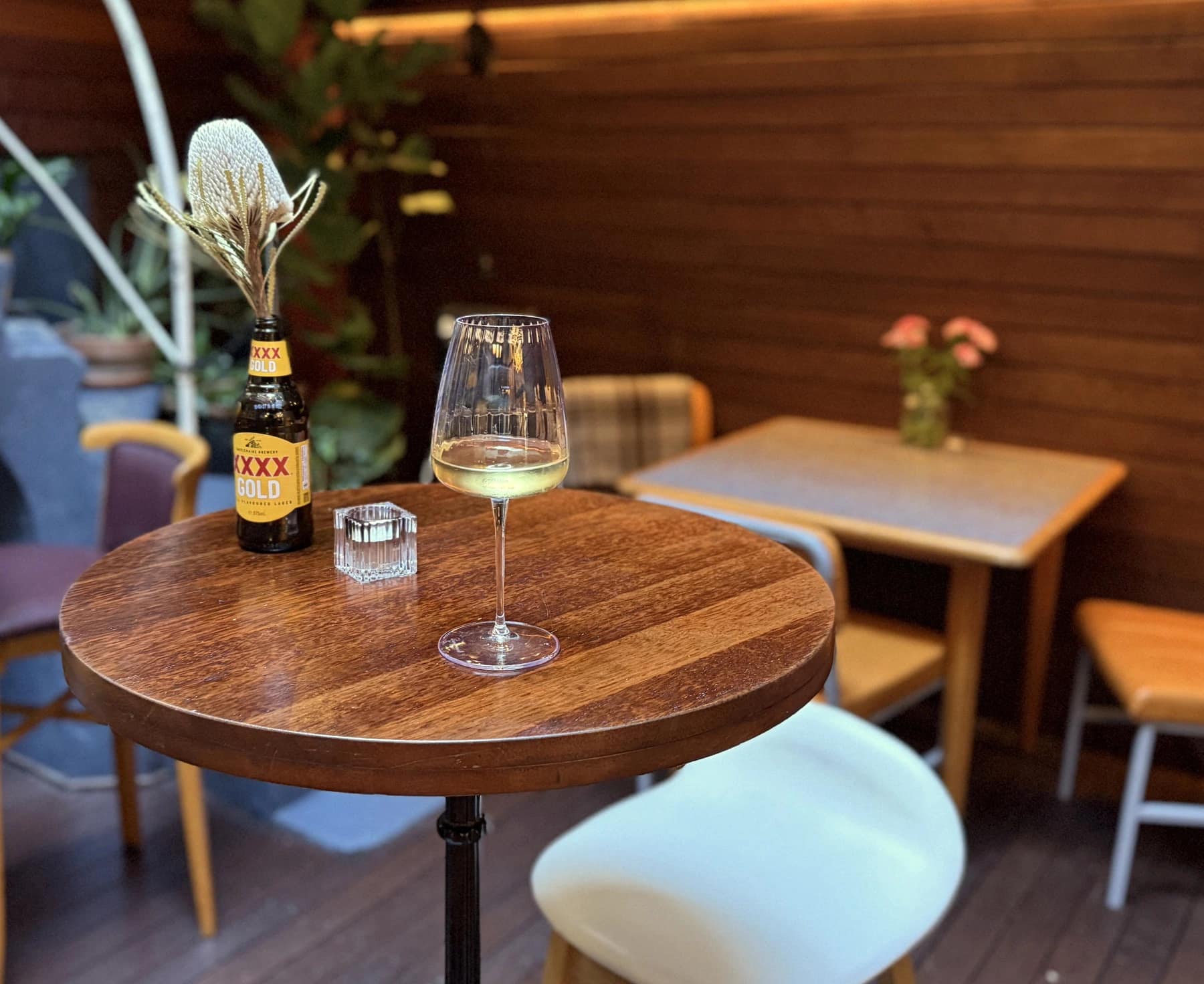 Wine and a flower-filled bottle on a table in Bar Lou Lou courtyard