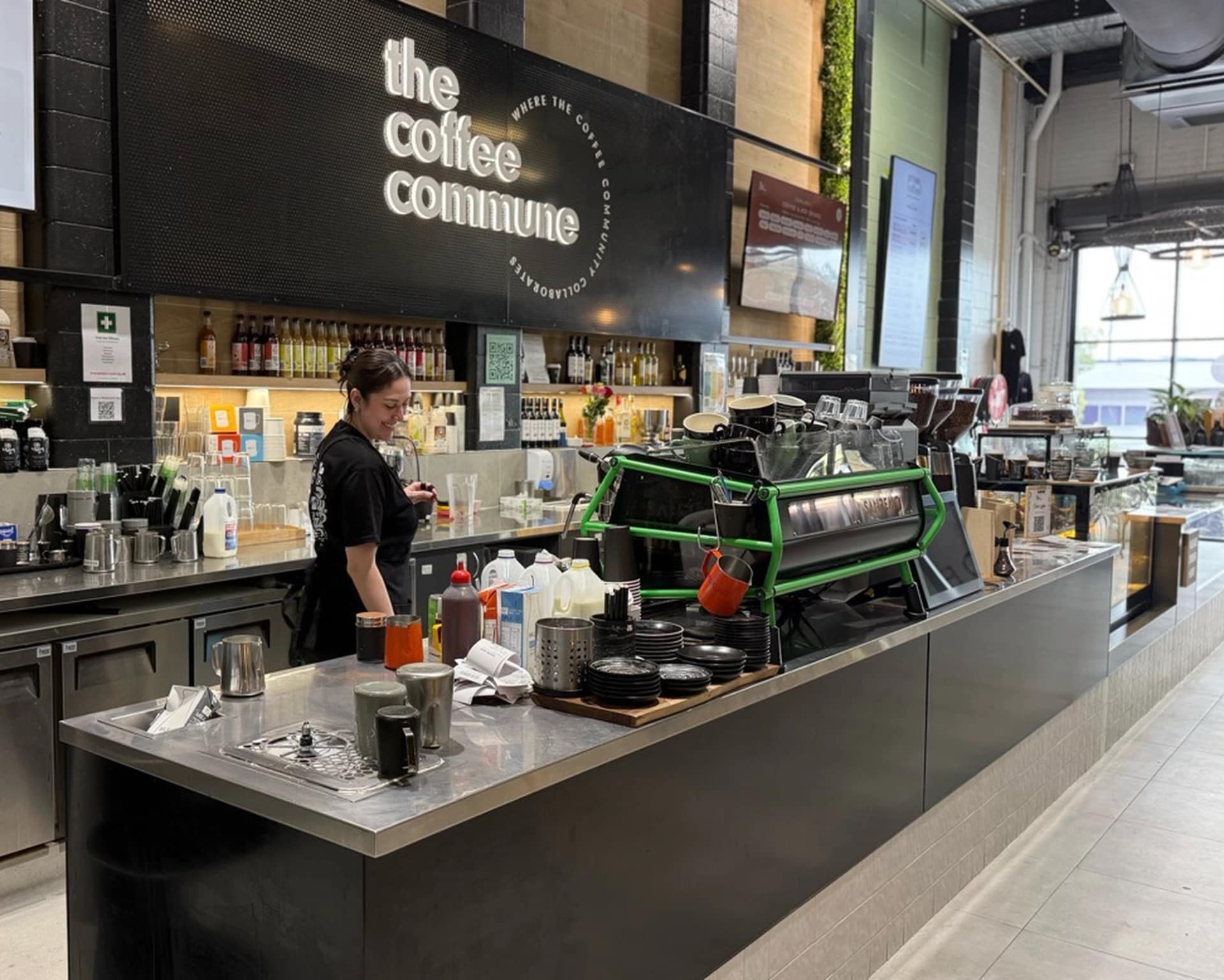 A barista working behind the cafe counter at The Coffee Commune