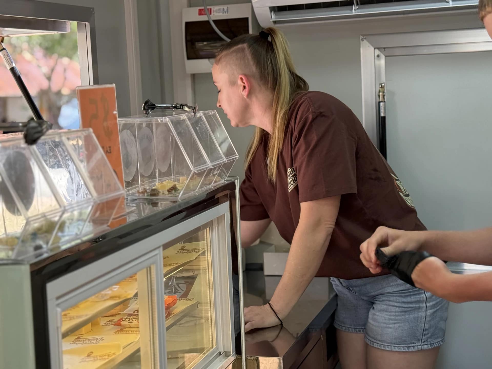 Sarah leaning forward at the serving window beside the fudge display