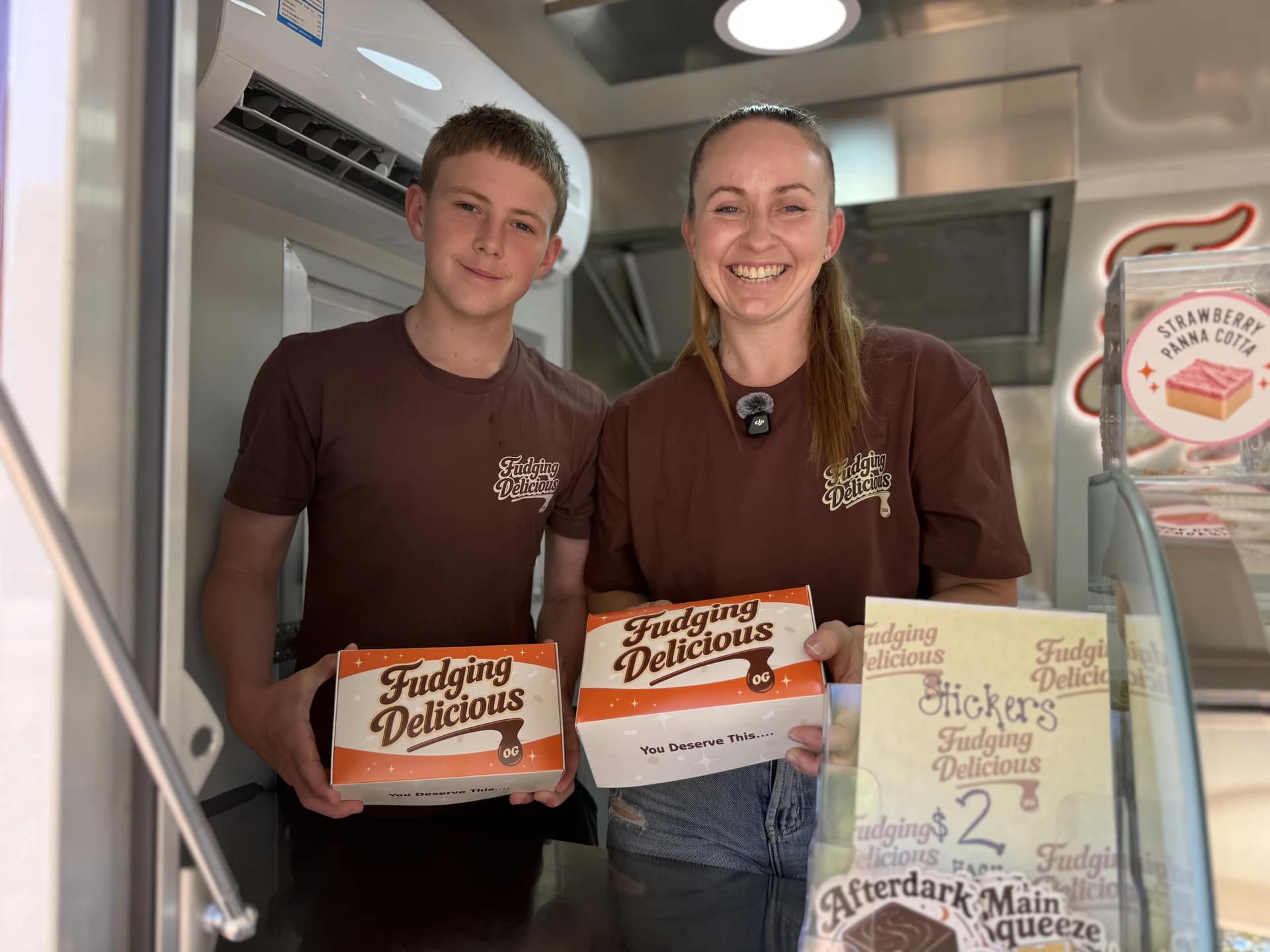 Sarah and her son Sam smiling together and holding Fudging Delicious boxes