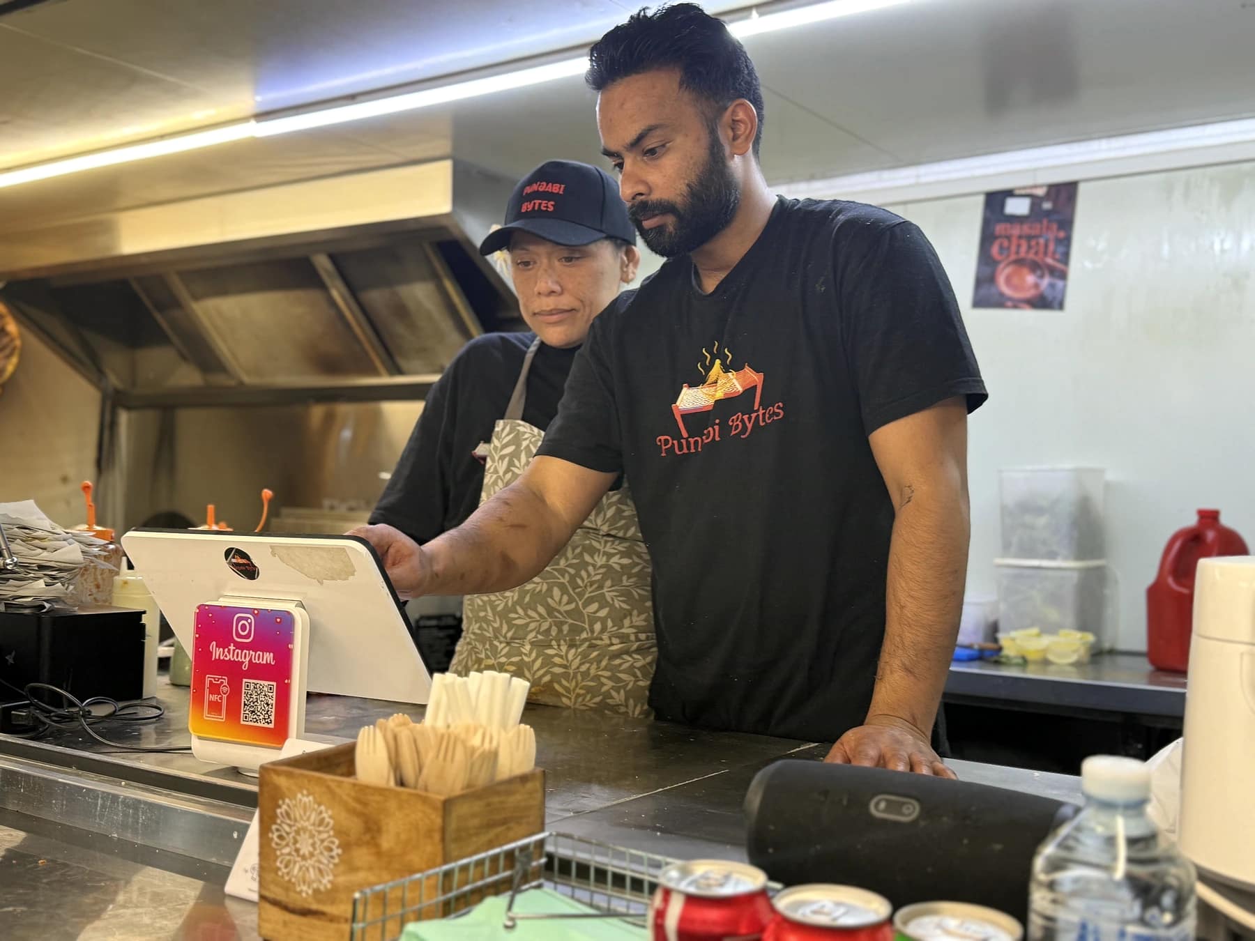 Satinder Singh and Sarah Nikola working during service inside the Punjabi Bytes trailer