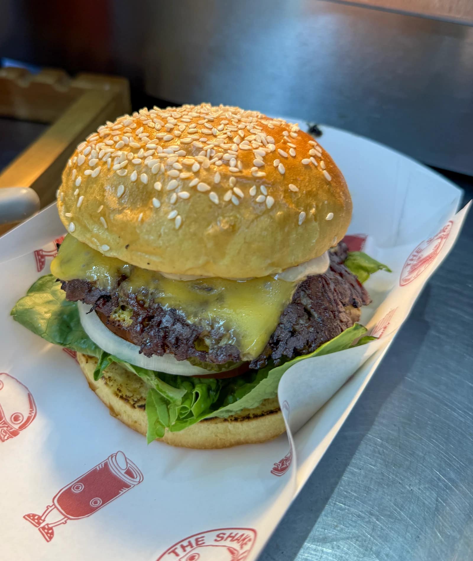 The OG burger in an open takeaway box, with cheese, patties and pickles visible.