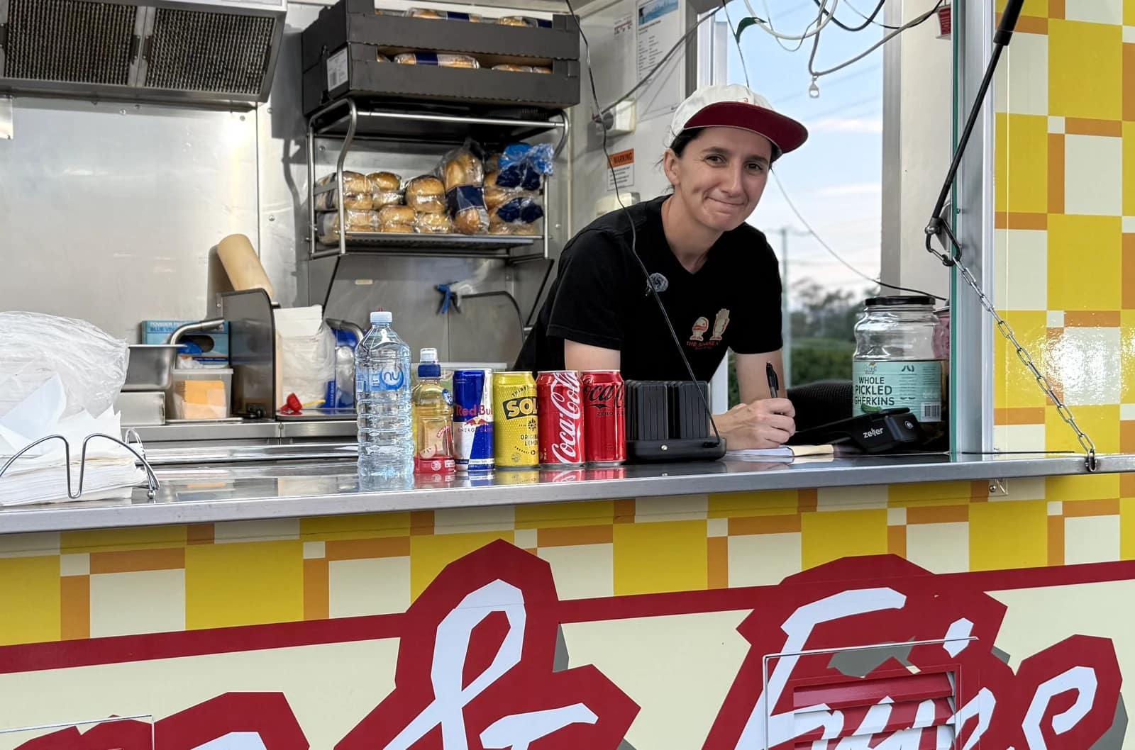 Atiana leaning at the serving window of The Shake Up’s yellow and red food truck.