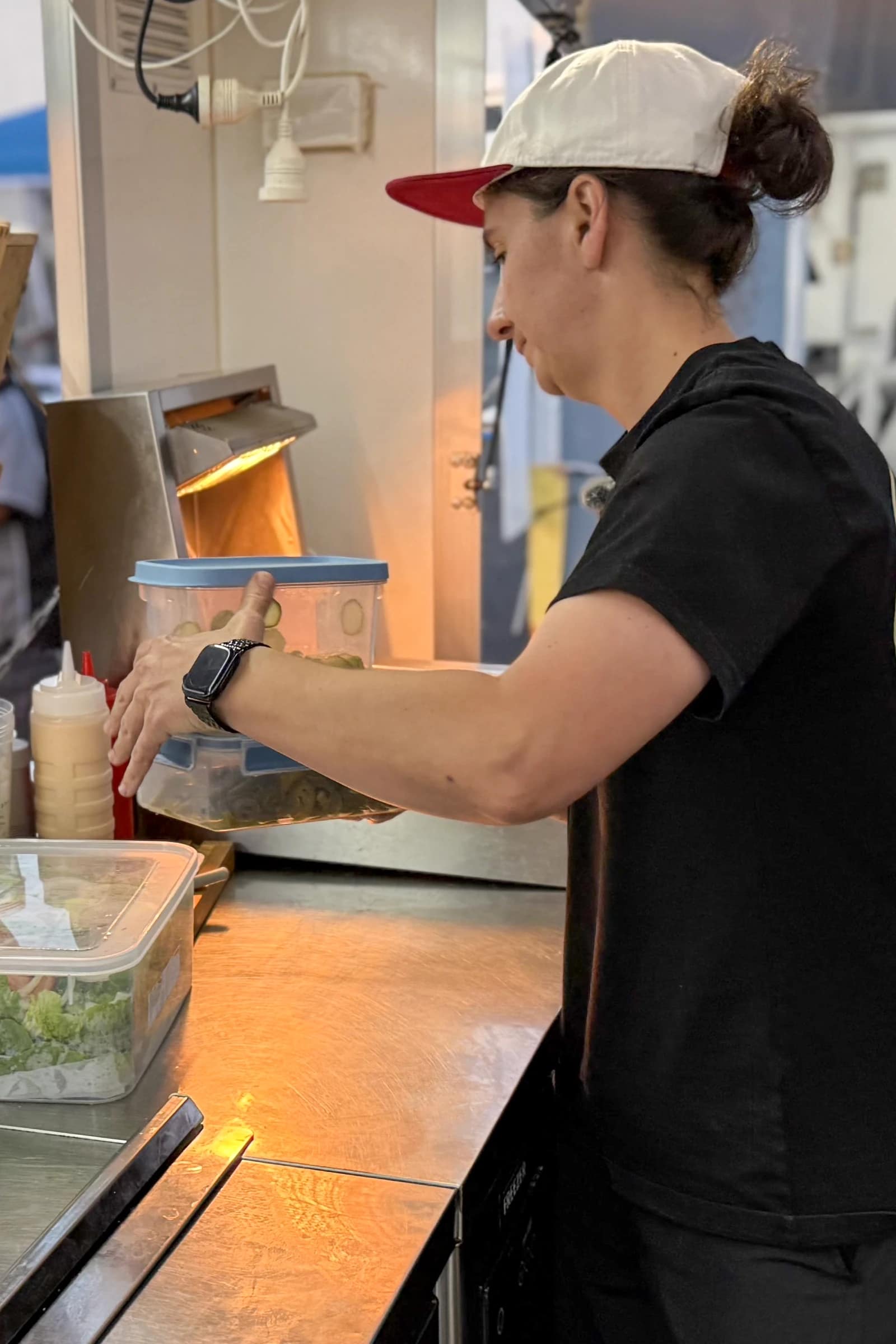 Atiana working with food containers at the preparation counter inside The Shake Up truck.