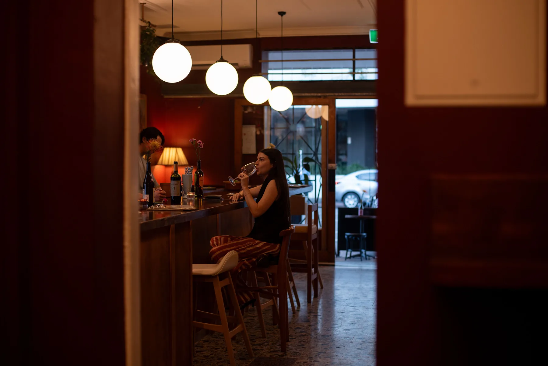 Guests at the timber bar beneath Bar Lou Lou's orb pendant lights on Barry Parade