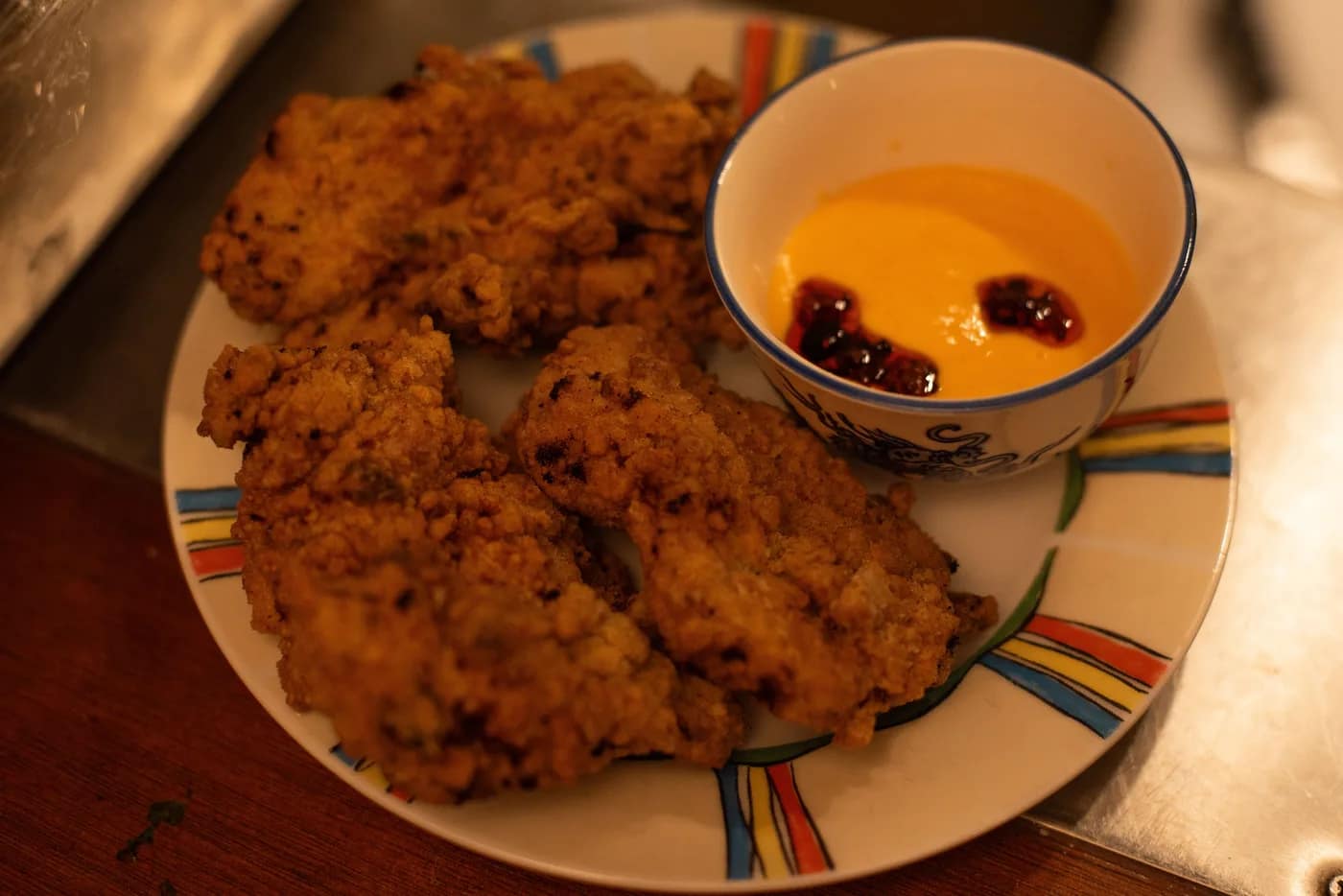 Crispy fried chicken with a dipping sauce at Bar Lou Lou