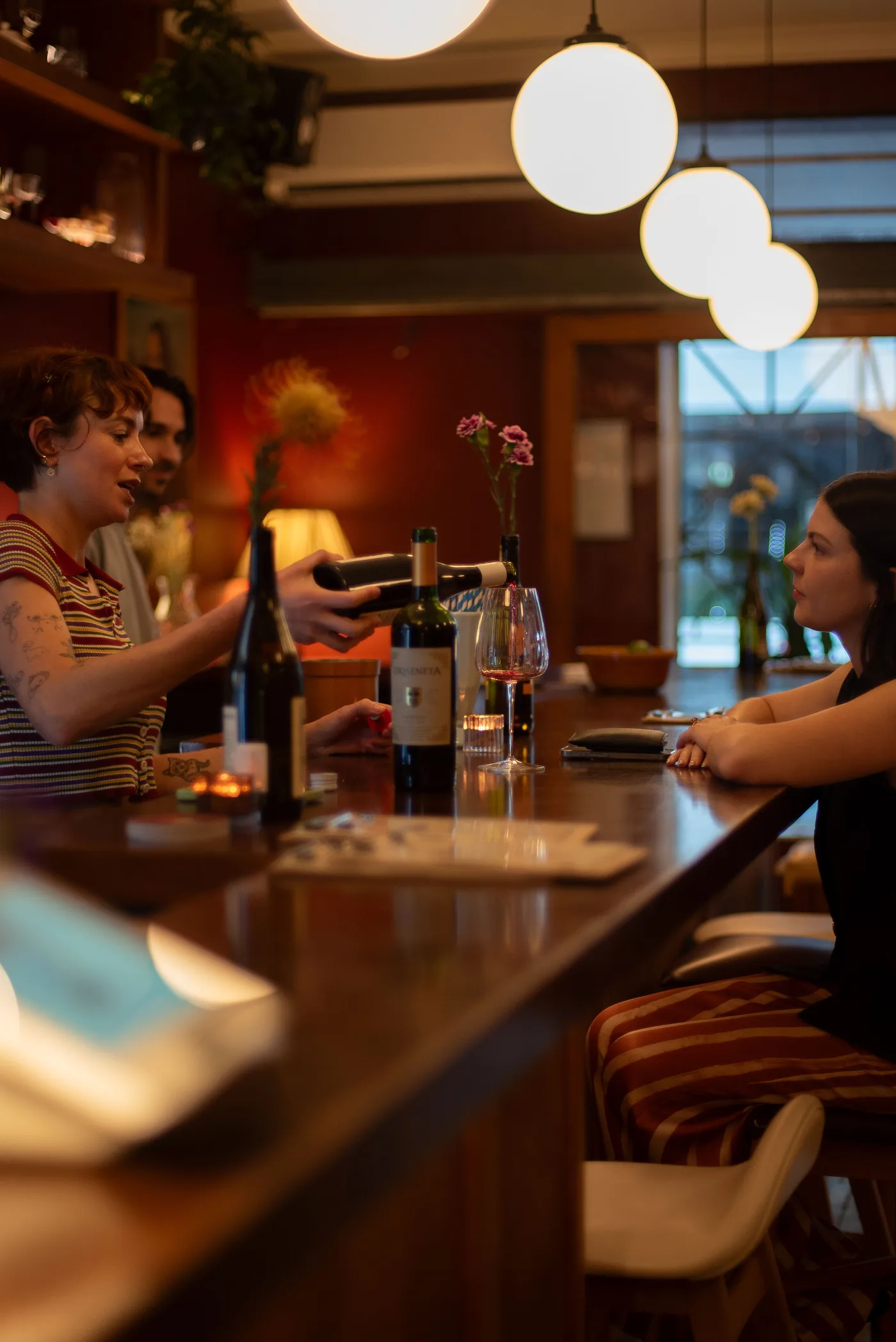 Friends sharing a bottle of wine at the bar inside Bar Lou Lou