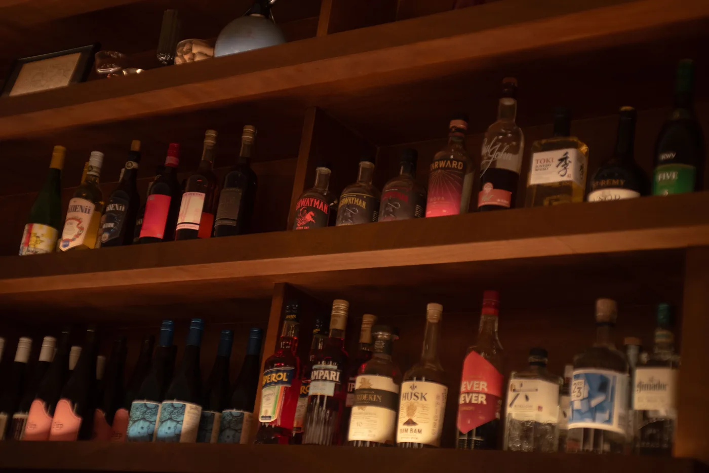 Wine and spirit bottles lined up on the back-bar shelves at Bar Lou Lou