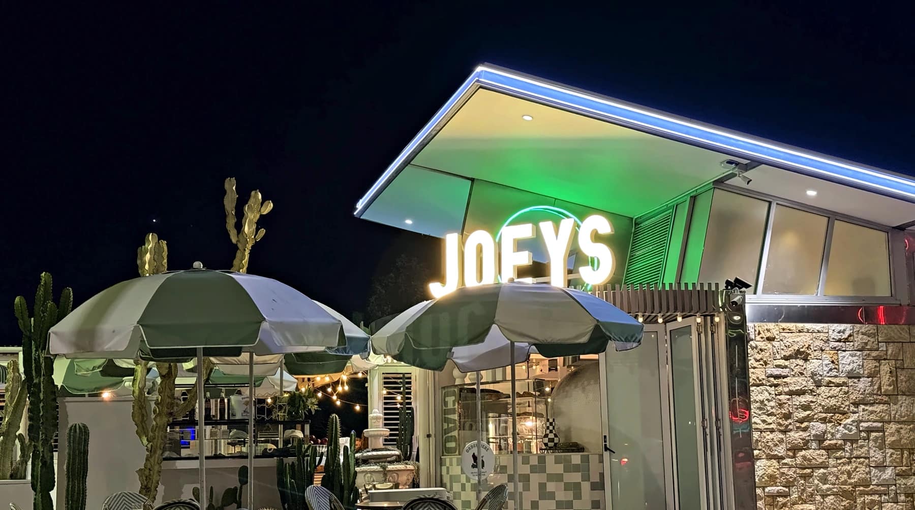 Joey's illuminated sign and green-and-white terrace umbrellas on River Terrace, Kangaroo Point, at night