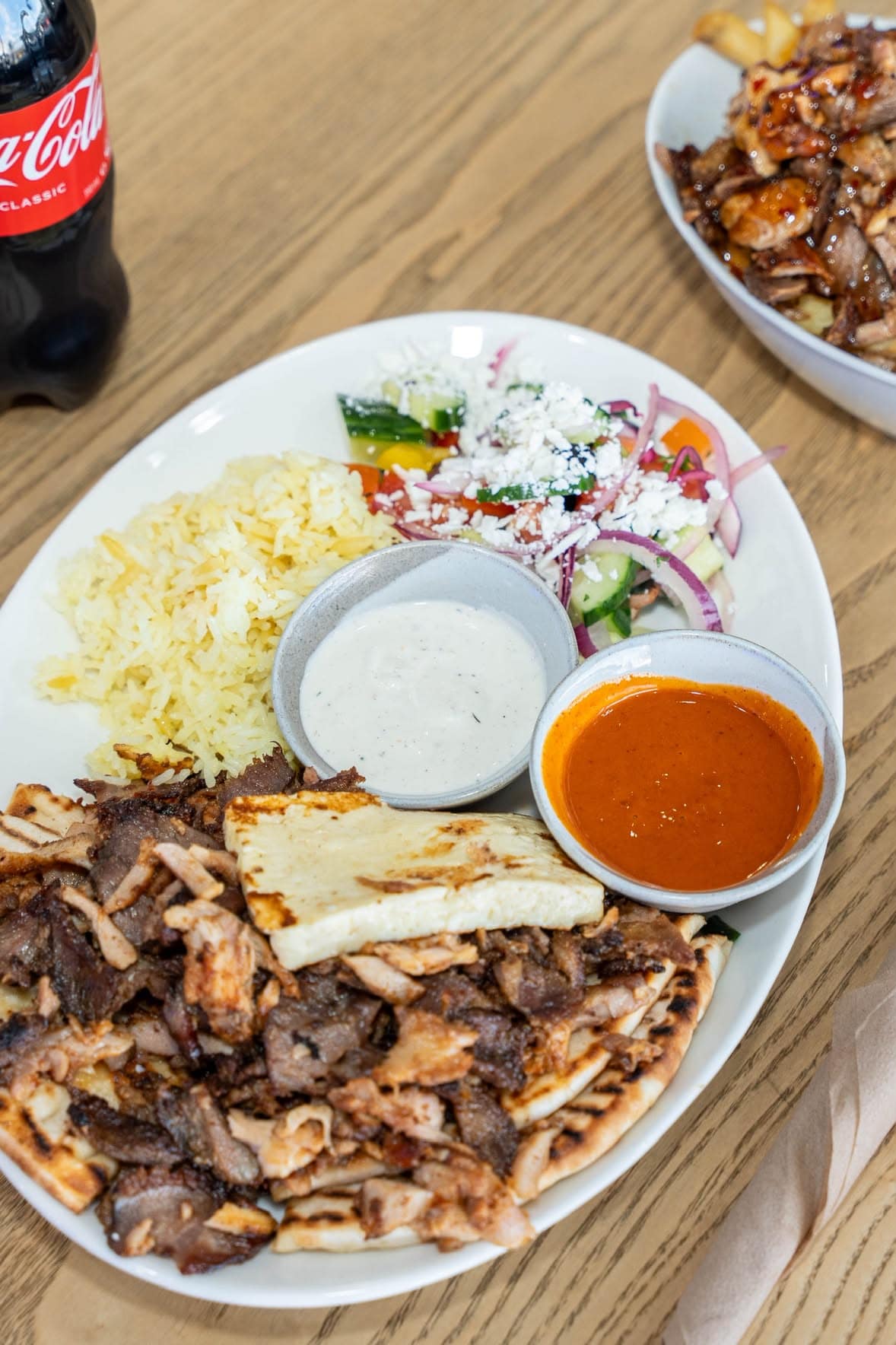 A plated meal with meat, rice, salad, pita and sauces at Ozi Yiros