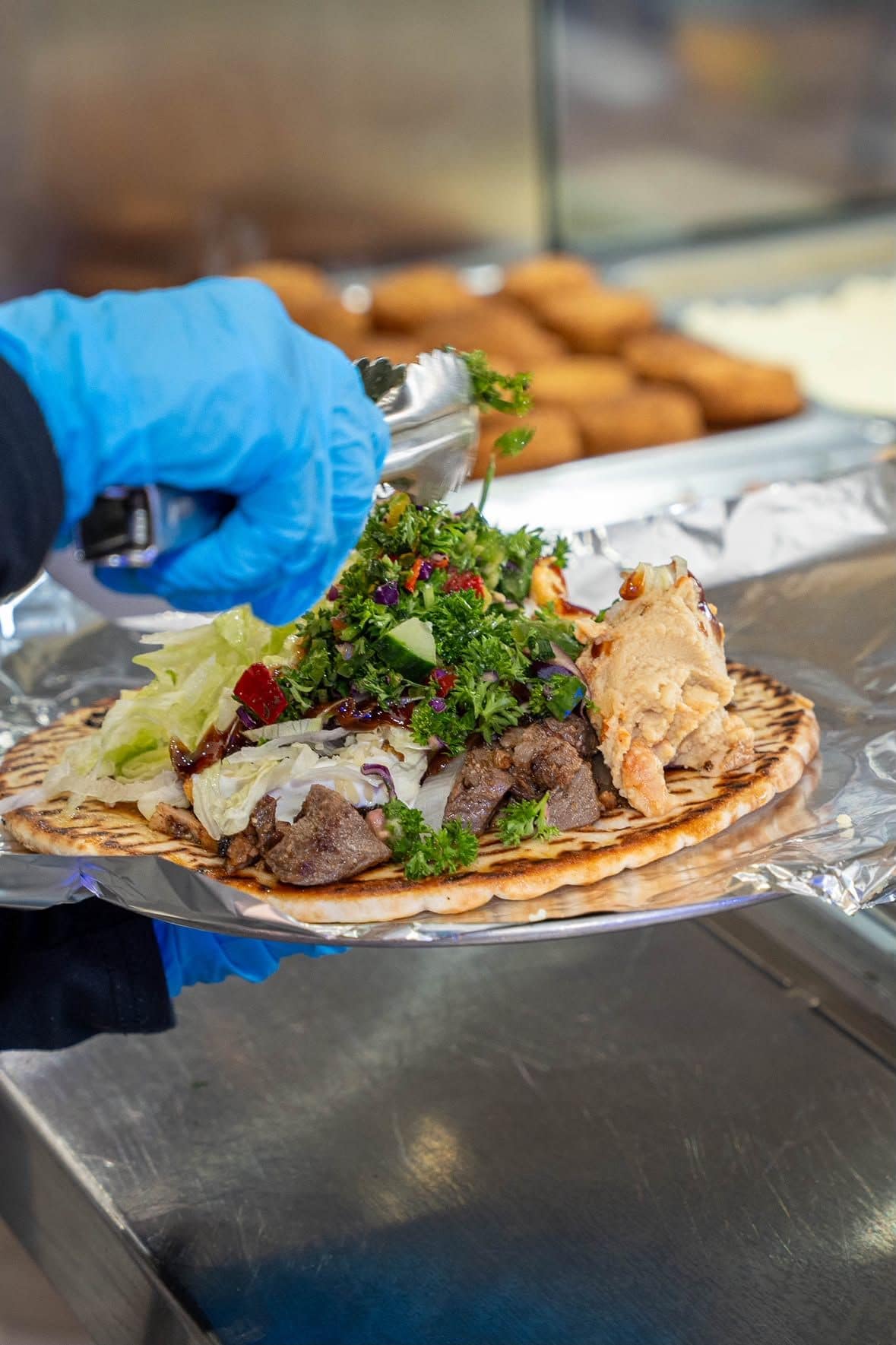 A yiros being prepared with chopped salad at Ozi Yiros