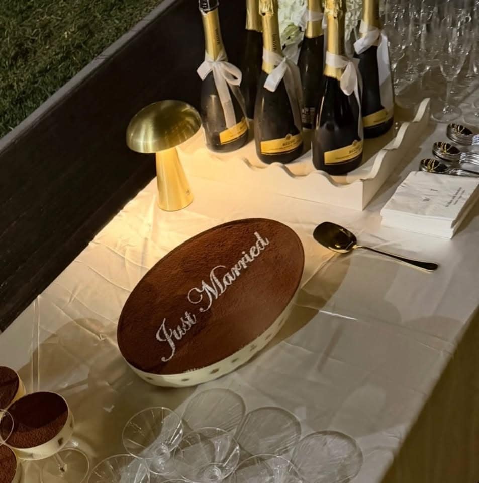 A "Just Married" tiramisu on a wedding table with champagne and tiramisu glasses