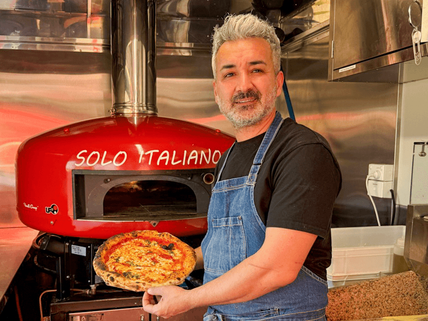 Chef Giann holding a pizza in front of the Solo Italiano oven