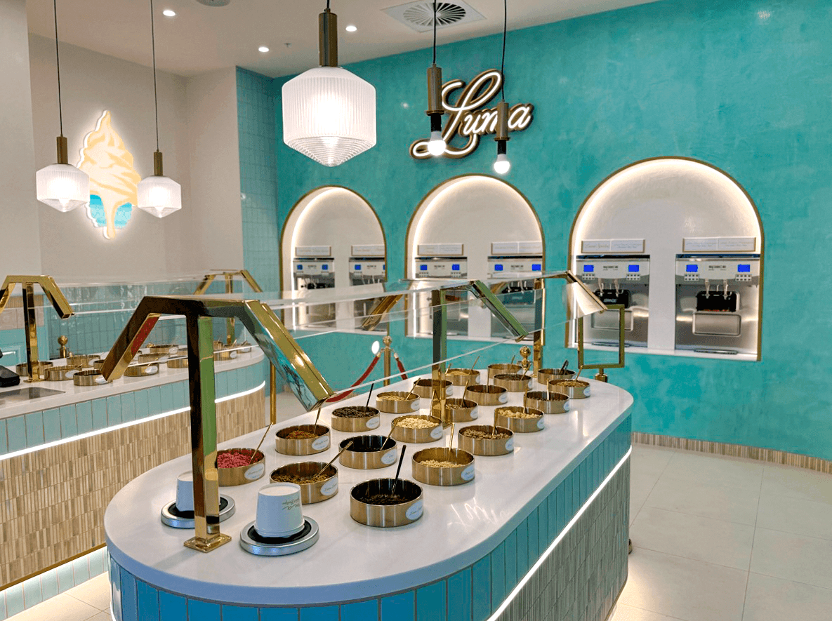 Curved topping counters in front of six gelato machine units in three illuminated alcoves at Luma Newstead