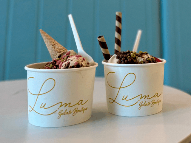Two branded Luma gelato cups on a table in front of mint-coloured seating