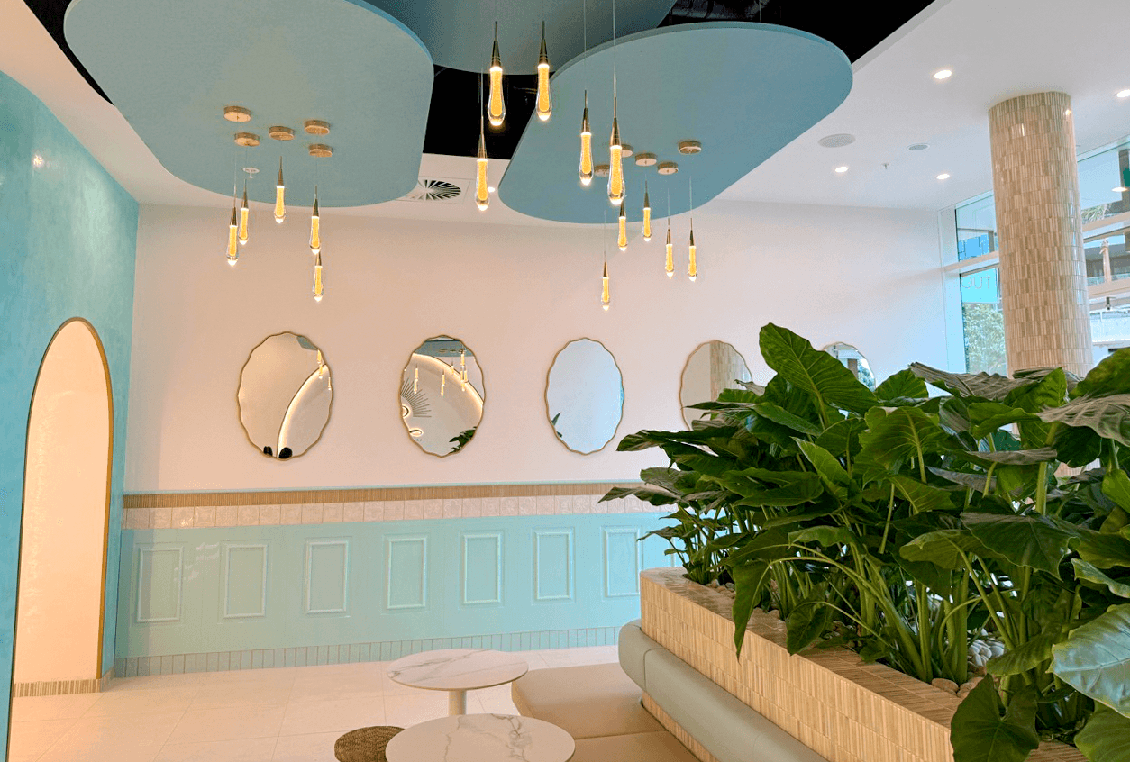 A wider view of Luma's mint panelling, gold-edged mirrors, pendant lights and planted seating area