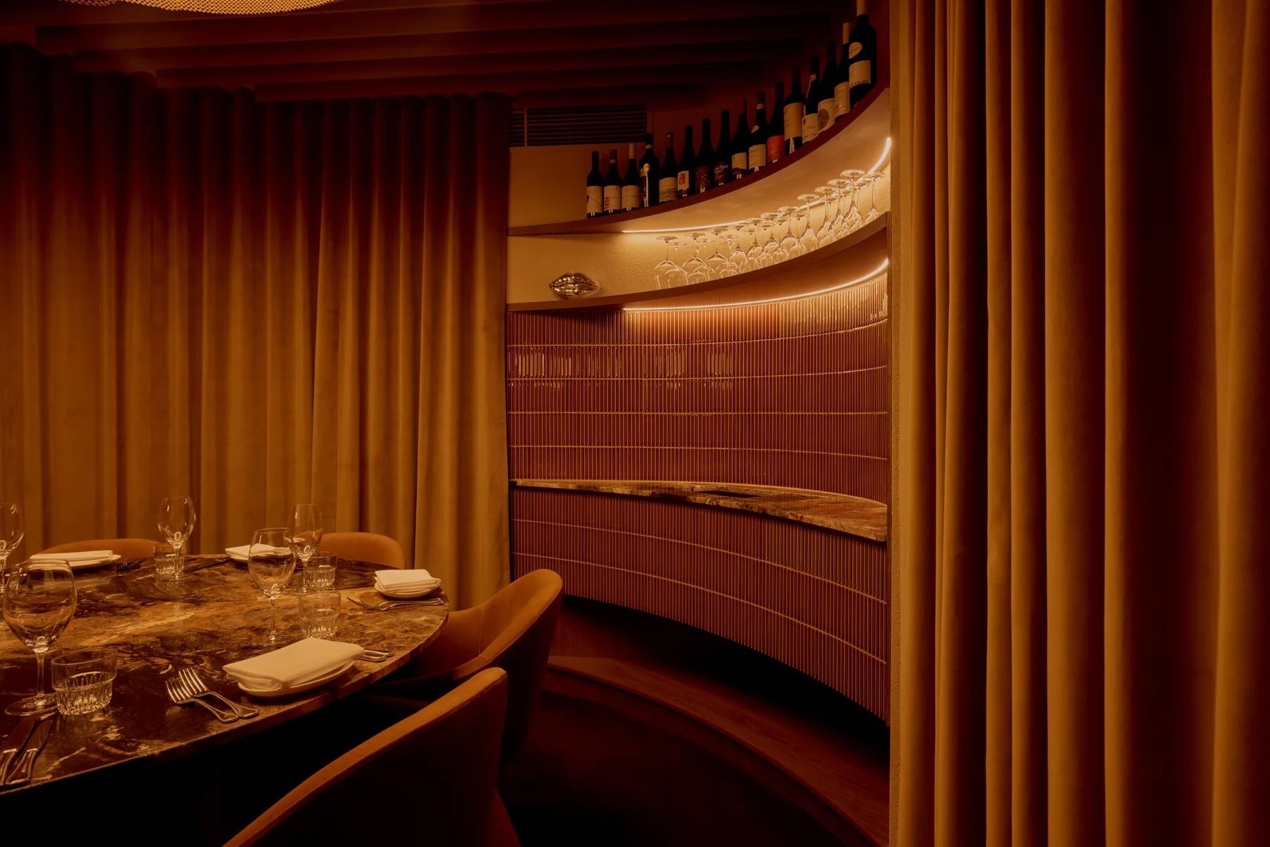 A private dining table framed by amber curtains inside Penelope