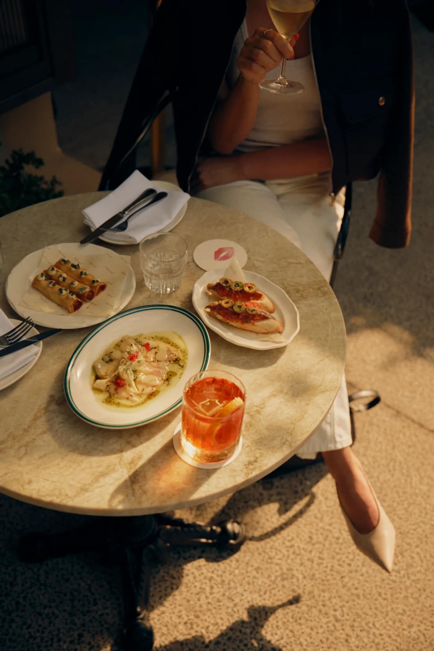 Drinks and small plates on a sunlit table at Penelope