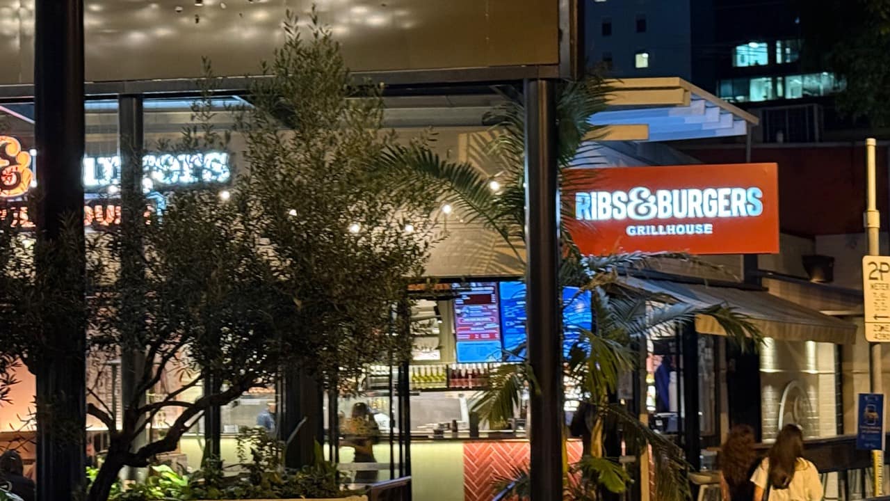 The illuminated Ribs and Burgers sign and dining area on James Street