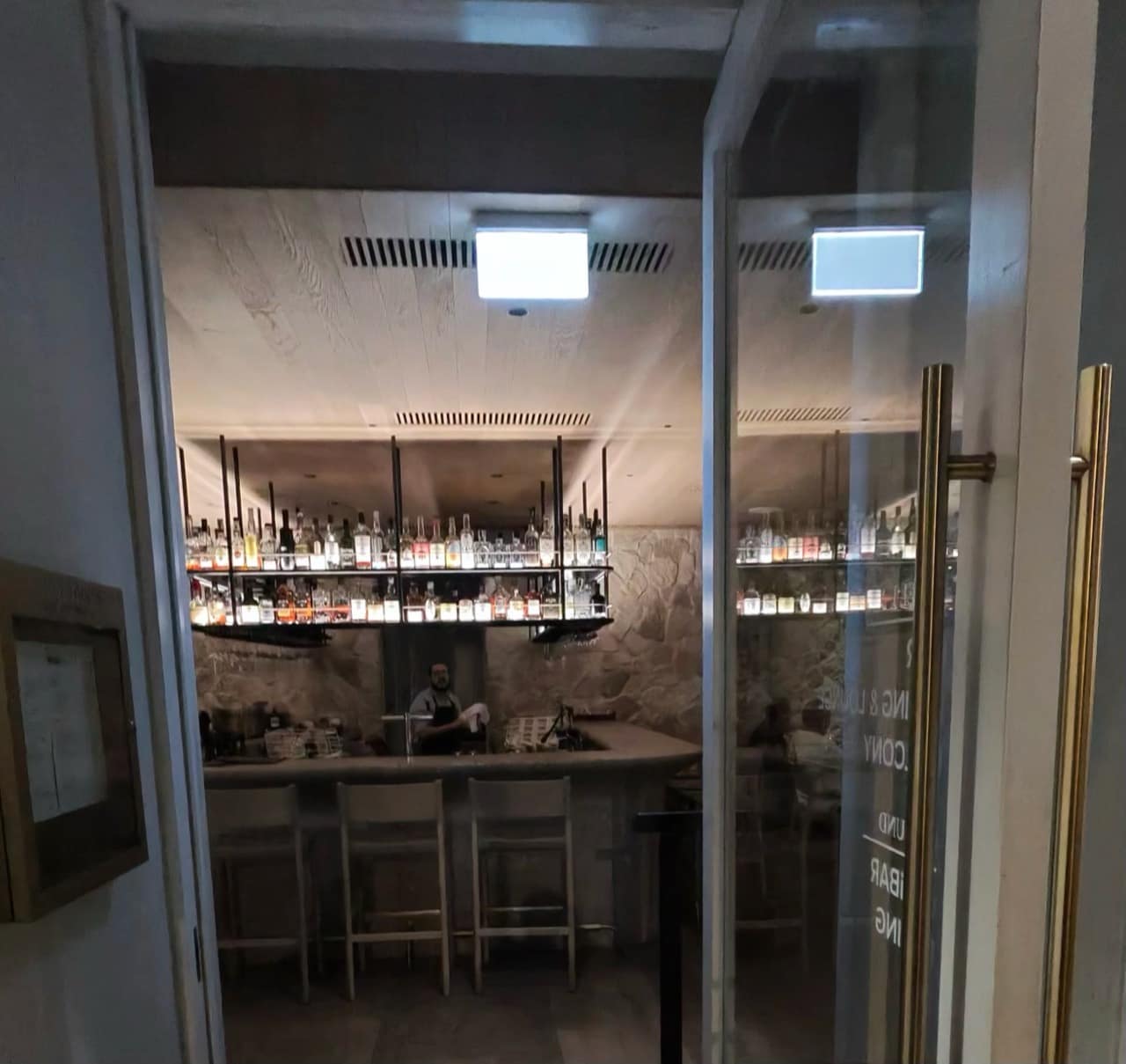 Looking through the doorway at the stone bar and suspended bottle shelves inside The Lodge